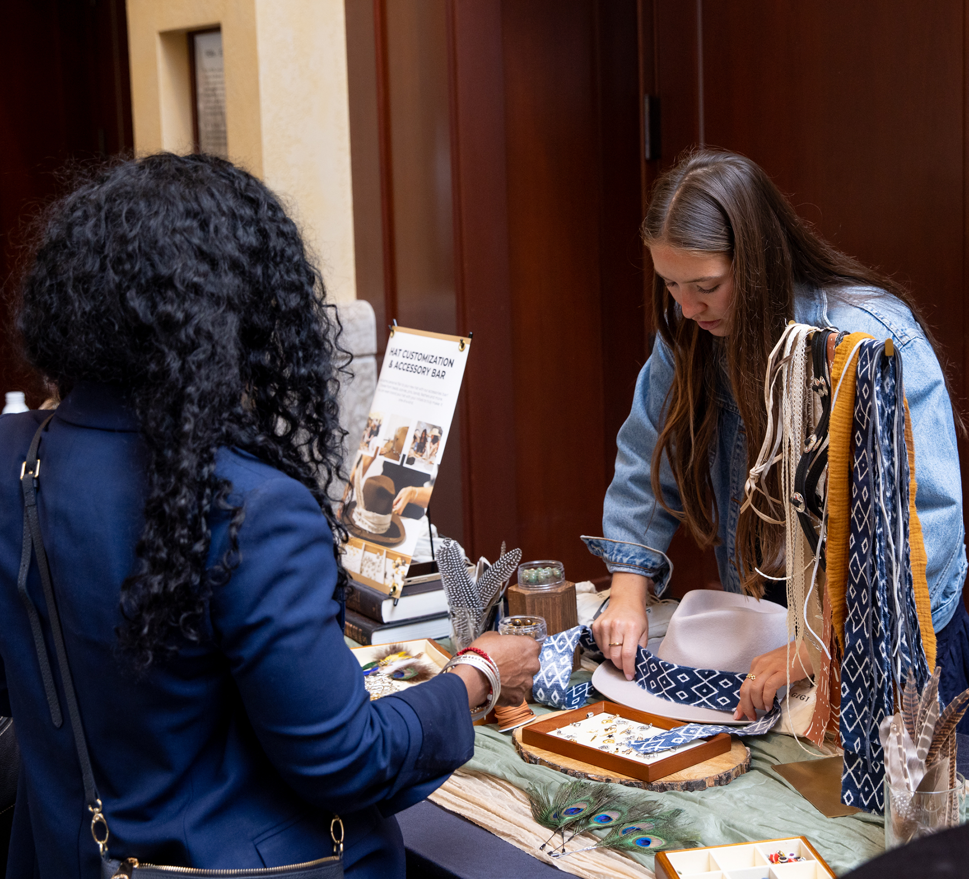 Guest at a gifting event works with a Global Evento Employee to design a custom felt hat.