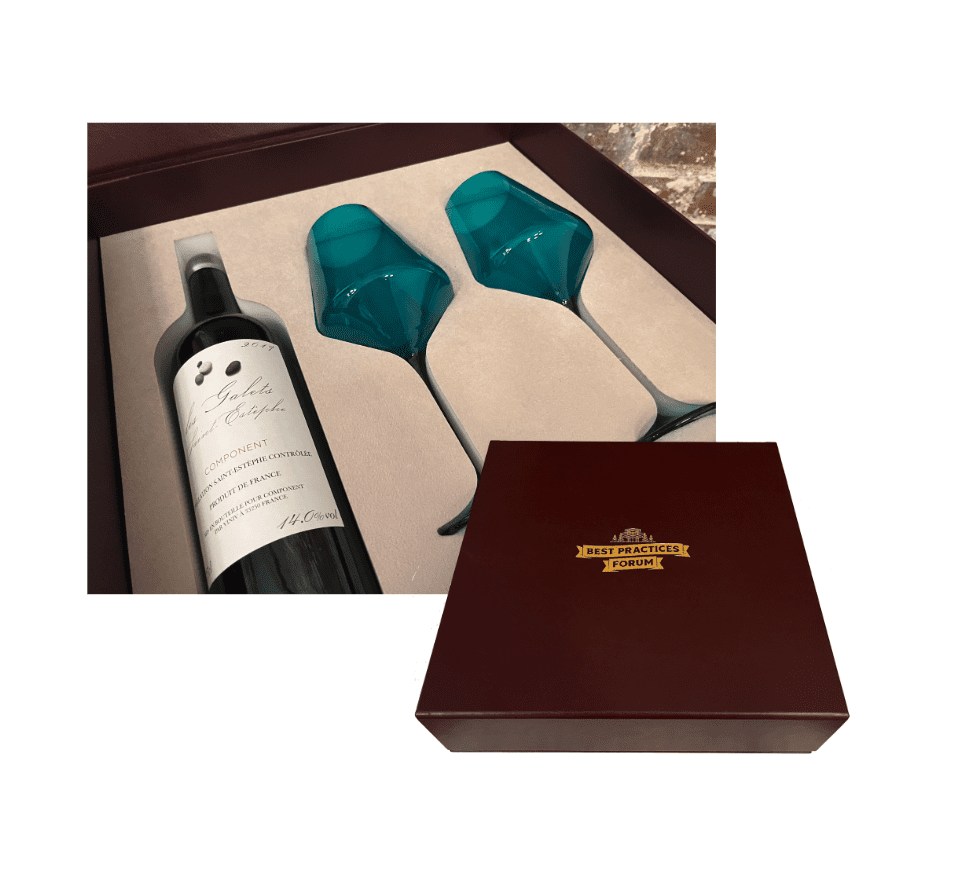 A cutout image of a maroon box with a gold logo overlaps an image of the box interior, which features a bottle of wine and two teal wine glasses.